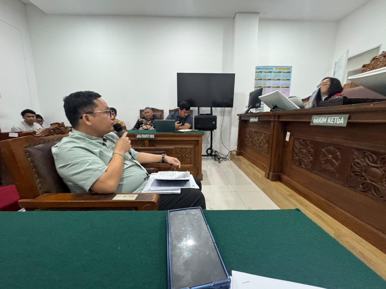 Ryanto Piter duduk di hadapan majelis hakim dan memberikan keterangan melalui mikrofon di ruang sidang